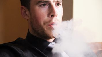 Ryan Billingham, 25, uses an electronic cigarette at his home in Columbus, Ohio. A new national survey shows 54% of men under age 35 think electronic cigarettes are less harmful to the lungs than cigarettes, but doctors aren`t sure.